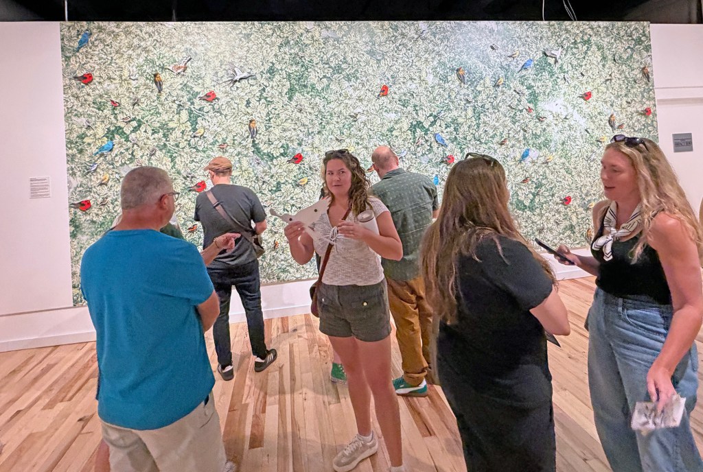 a group of people standing in front of a green wall and talking